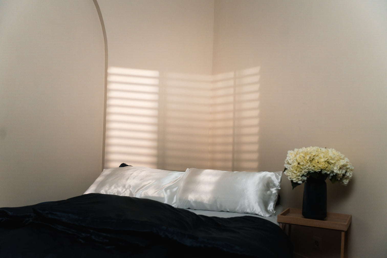 Leeres Bett, auf welches der Schatten einer Jalousie geworfen wird